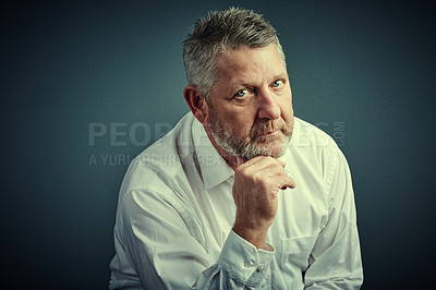 Buy stock photo Studio portrait of a handsome mature businessman looking thoughtful while sitting down against a dark background