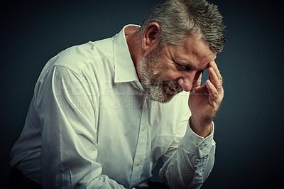 Buy stock photo Studio shot of a mature businessman looking stressed while sitting down against a dark background