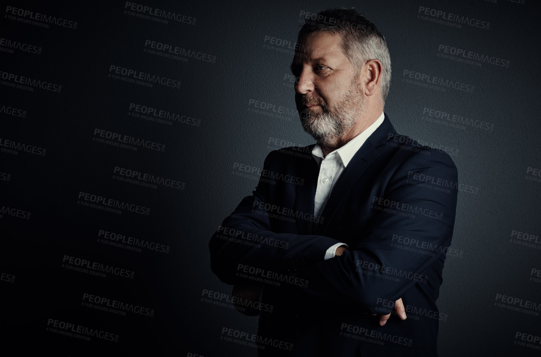 Buy stock photo Studio shot of a handsome mature businessman looking thoughtful while standing with his arms folded against a dark background