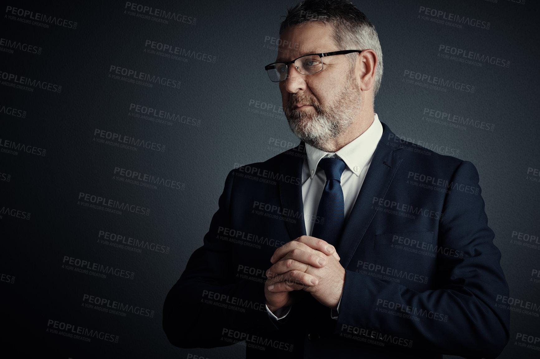 Buy stock photo Studio shot of a handsome mature businessman looking thoughtful while standing against a dark background