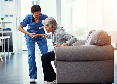 Buy stock photo Full length shot of a young female nurse helping her senior patient up from a chair in the old age home