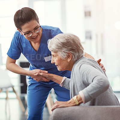 Buy stock photo Cropped shot of a young female nurse helping her senior patient up from a chair in the old age home