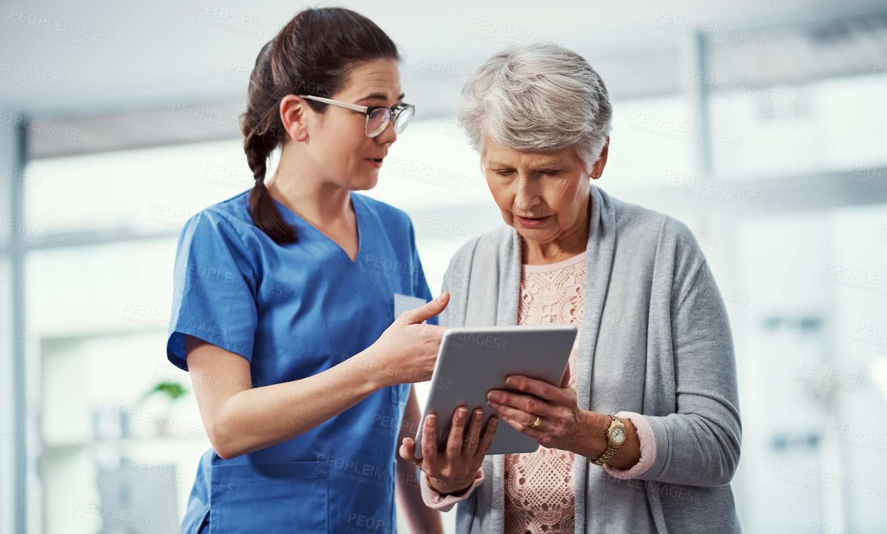 Buy stock photo Cropped shot of a young female nurse and her senior patient looking at a tablet in the old age home