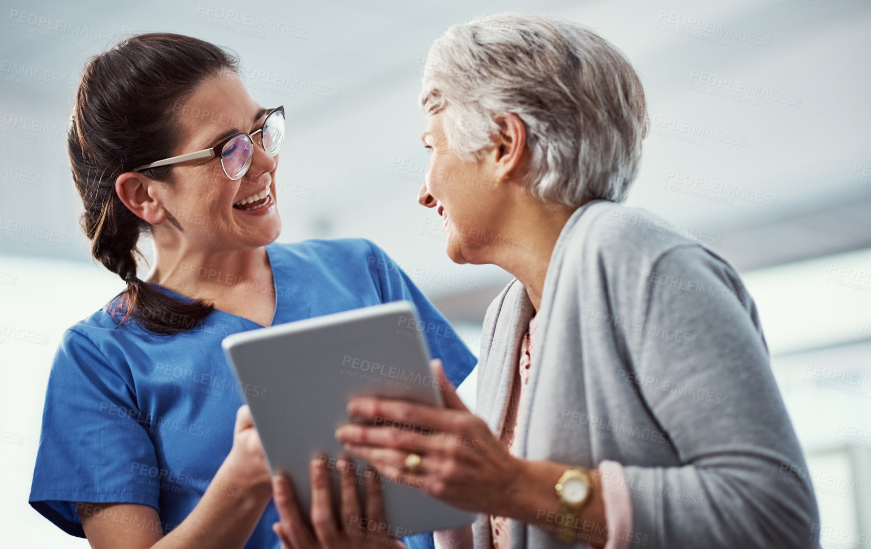 Buy stock photo Cropped shot of a young female nurse and her senior patient looking at a tablet in the old age home