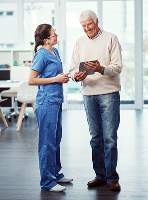 Buy stock photo Full length shot of a young female nurse and her senior patient looking at a tablet in the old age home