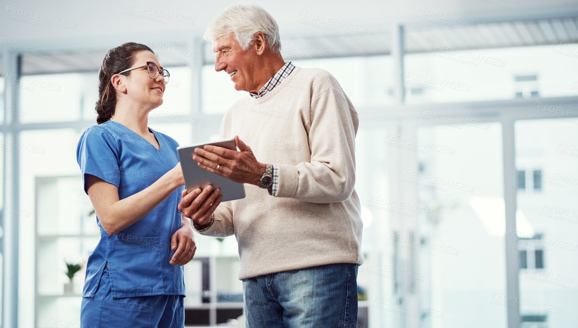 Buy stock photo Cropped shot of a young female nurse and her senior patient looking at a tablet in the old age home