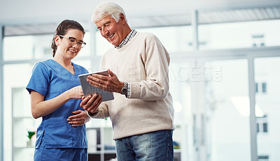 Buy stock photo Cropped shot of a young female nurse and her senior patient looking at a tablet in the old age home