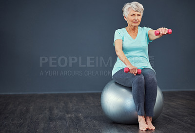 Buy stock photo Full length shot of a senior woman working out with dumbbells while sitting on an exercise ball