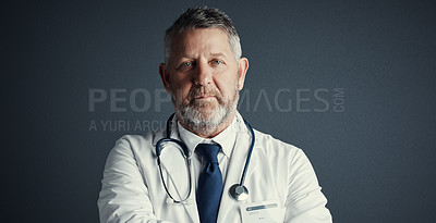 Buy stock photo Studio portrait of a handsome mature male doctor standing against a dark background