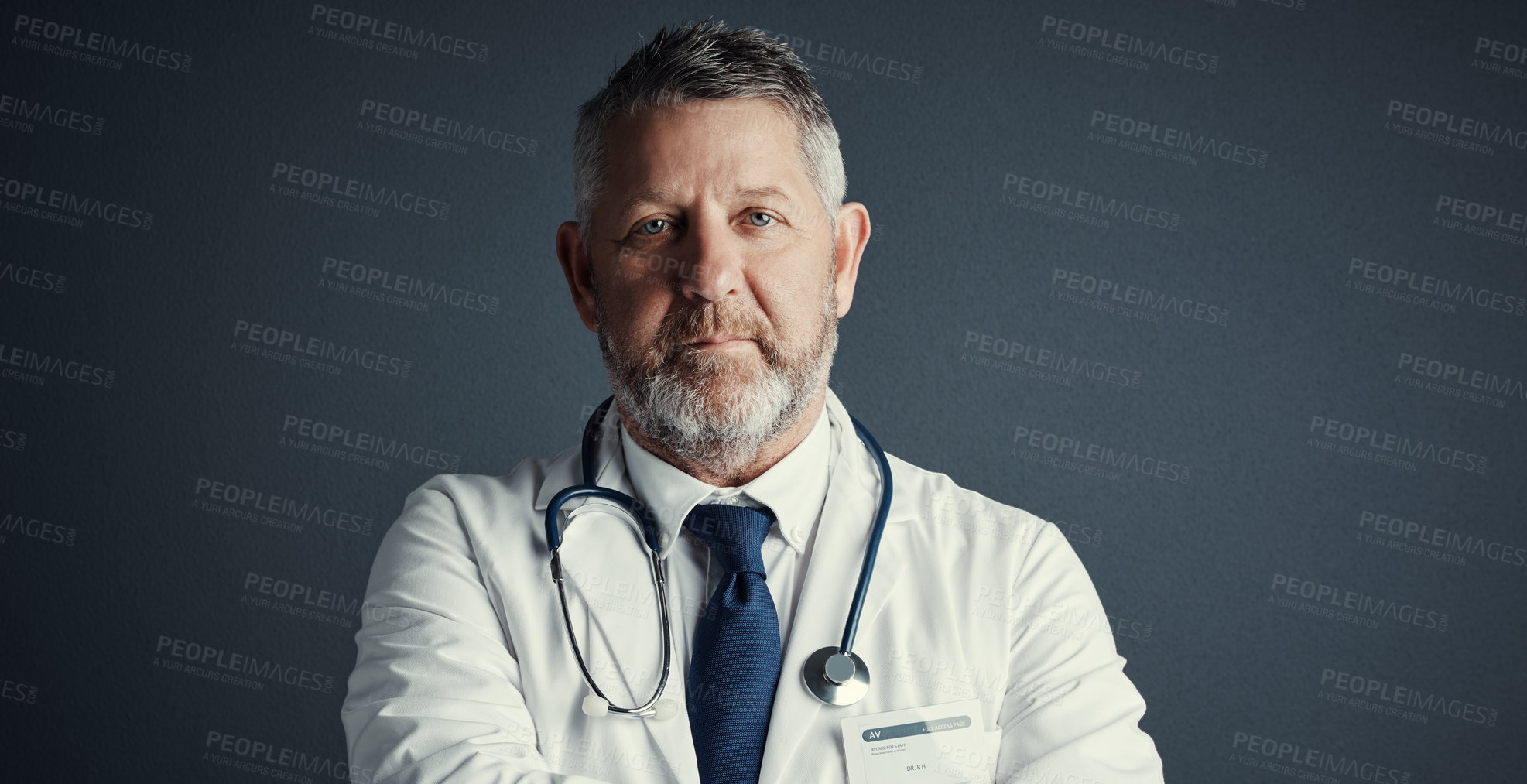 Buy stock photo Studio portrait of a handsome mature male doctor standing against a dark background