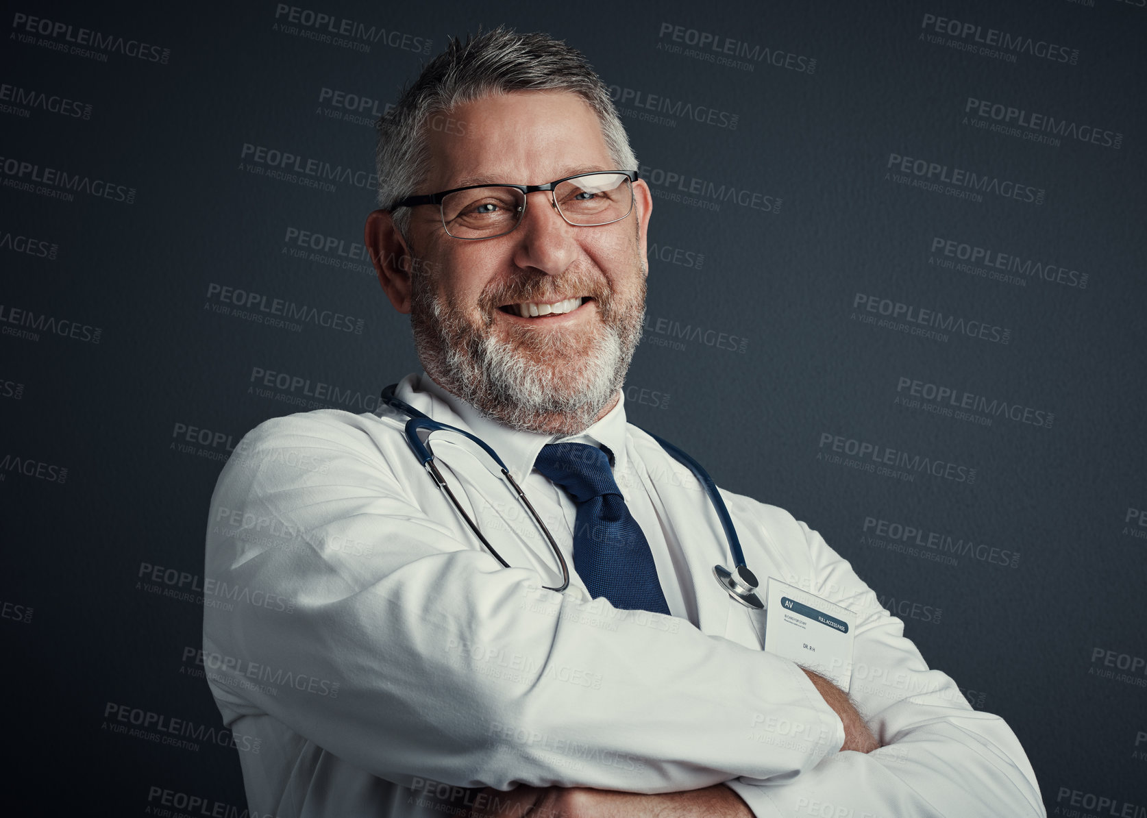 Buy stock photo Studio portrait of a handsome mature male doctor standing with his arms folded against a dark background