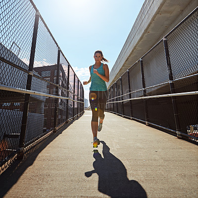 Buy stock photo Shot of a sporty young woman running on a footbridge