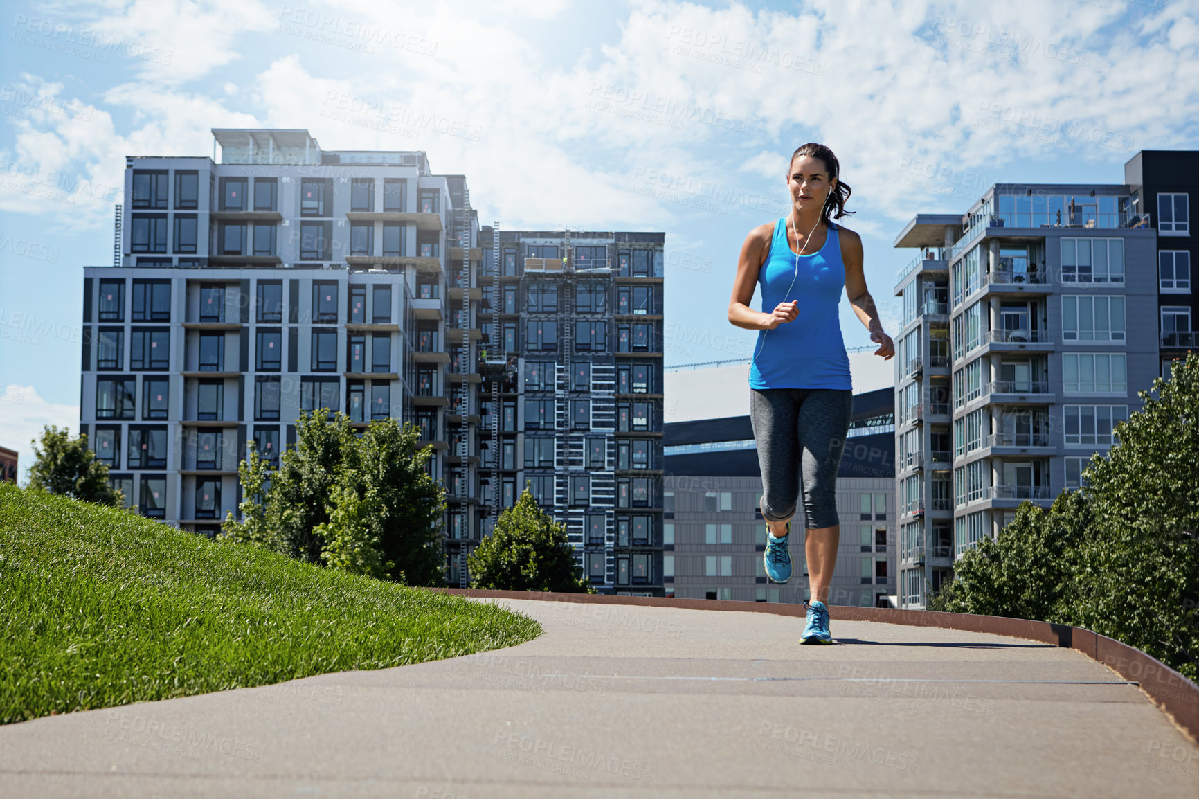 Buy stock photo Shot of a young woman listening to music while out running