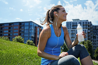 Buy stock photo Shot of a sporty young woman taking a break from her morning run