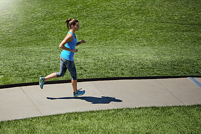 Buy stock photo Shot of a young woman listening to music while out running