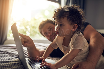 Buy stock photo Cropped shot of a father showing his baby daughter something on his laptop