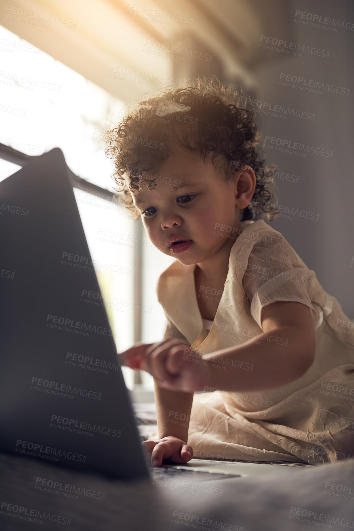 Buy stock photo Girl, toddler and laptop on bed with computer for curiosity, development games or e learning in bedroom. Lens flare, online and child with technology for entertainment, education or internet in home