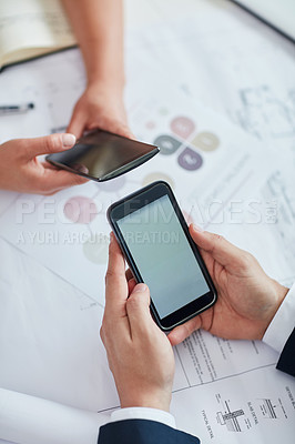 Buy stock photo Cropped shot of two businesspeople using their cellphones at a desk