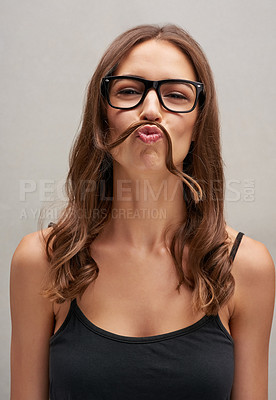 Buy stock photo Studio portrait of an attractive young woman posing with her hair over her lip against a grey background