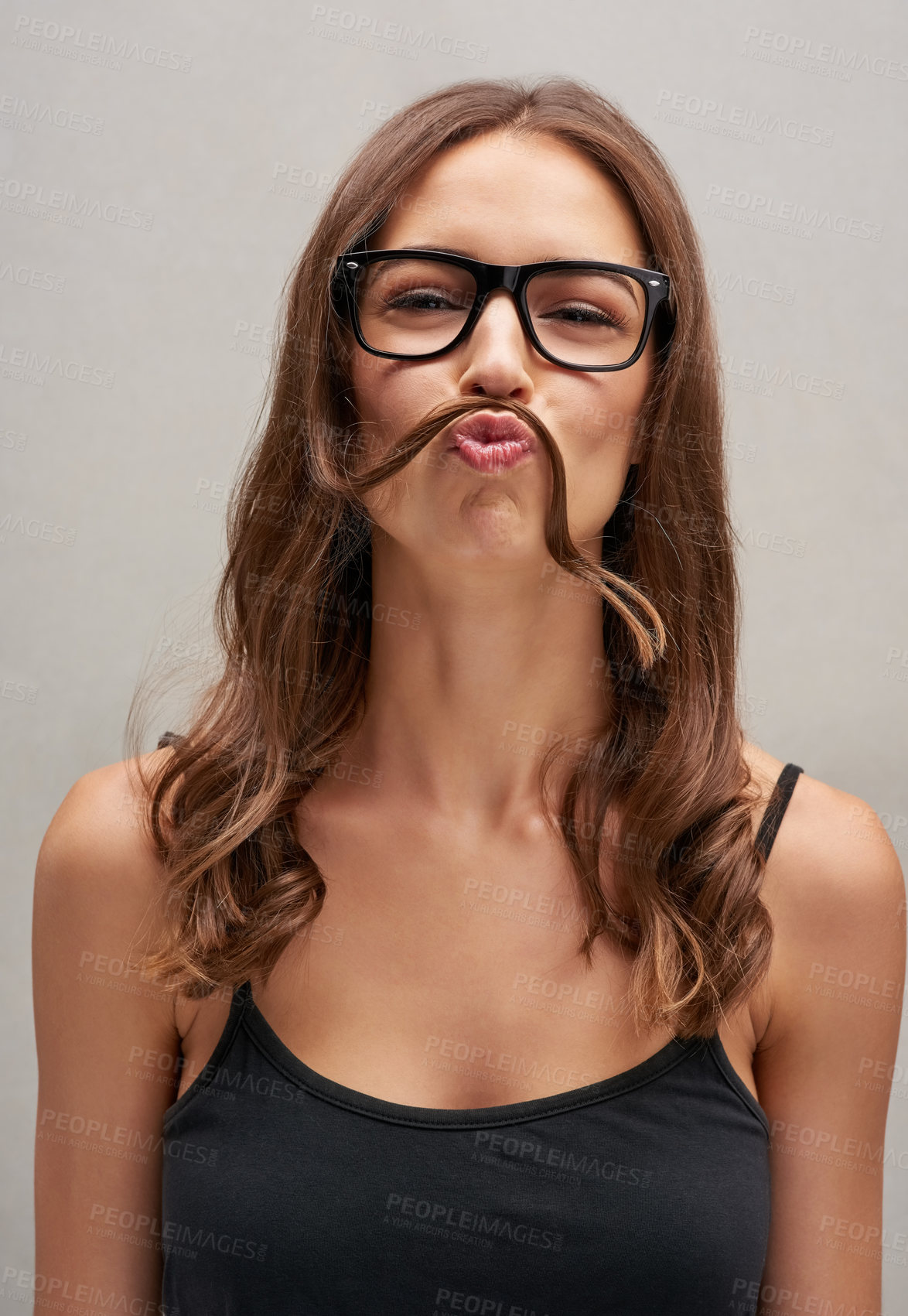 Buy stock photo Studio portrait of an attractive young woman posing with her hair over her lip against a grey background