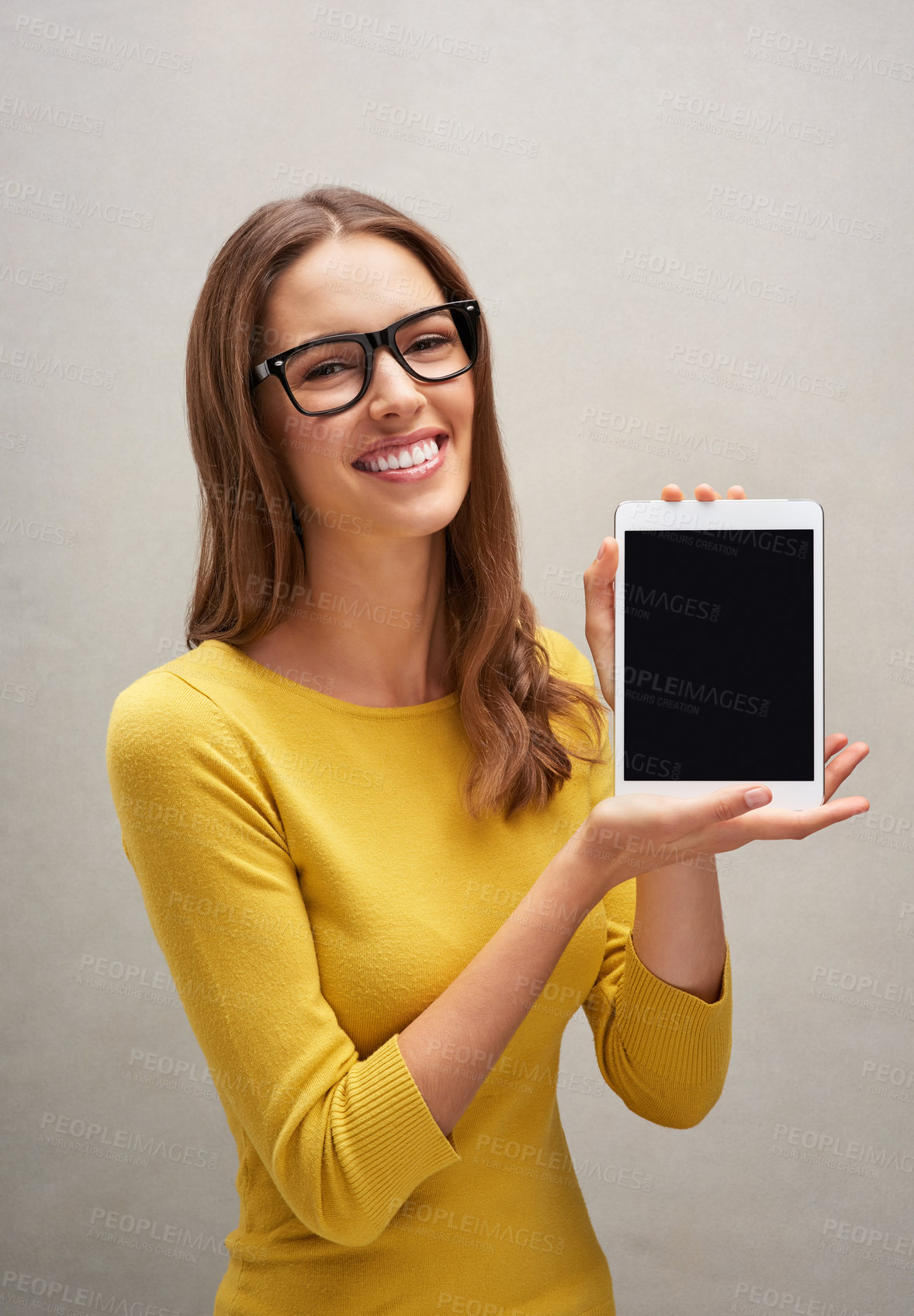 Buy stock photo Studio portrait of an attractive young woman posing with her tablet against a grey background