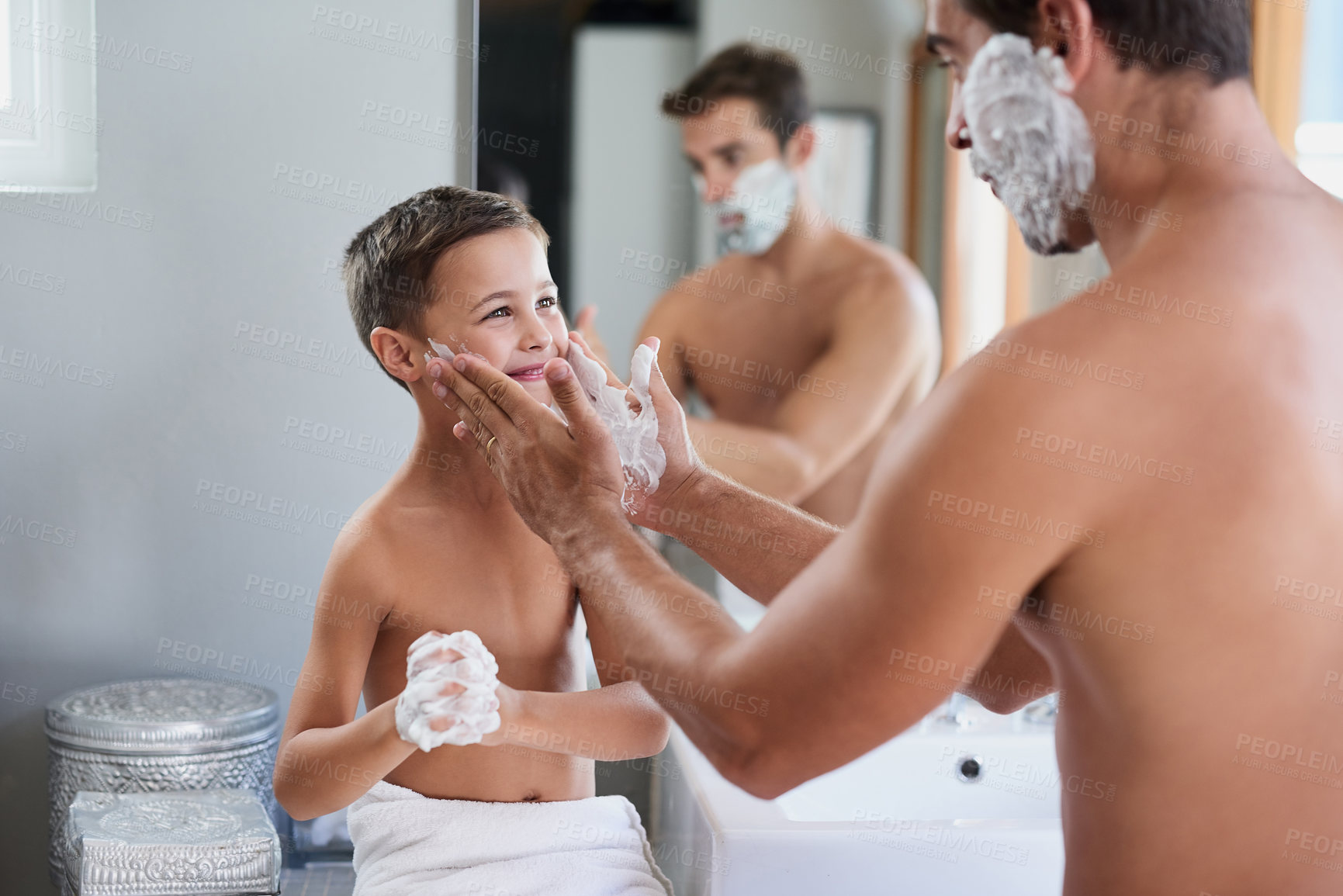 Buy stock photo Cropped shot of a handsome young man teaching his son how to shave in the bathroom