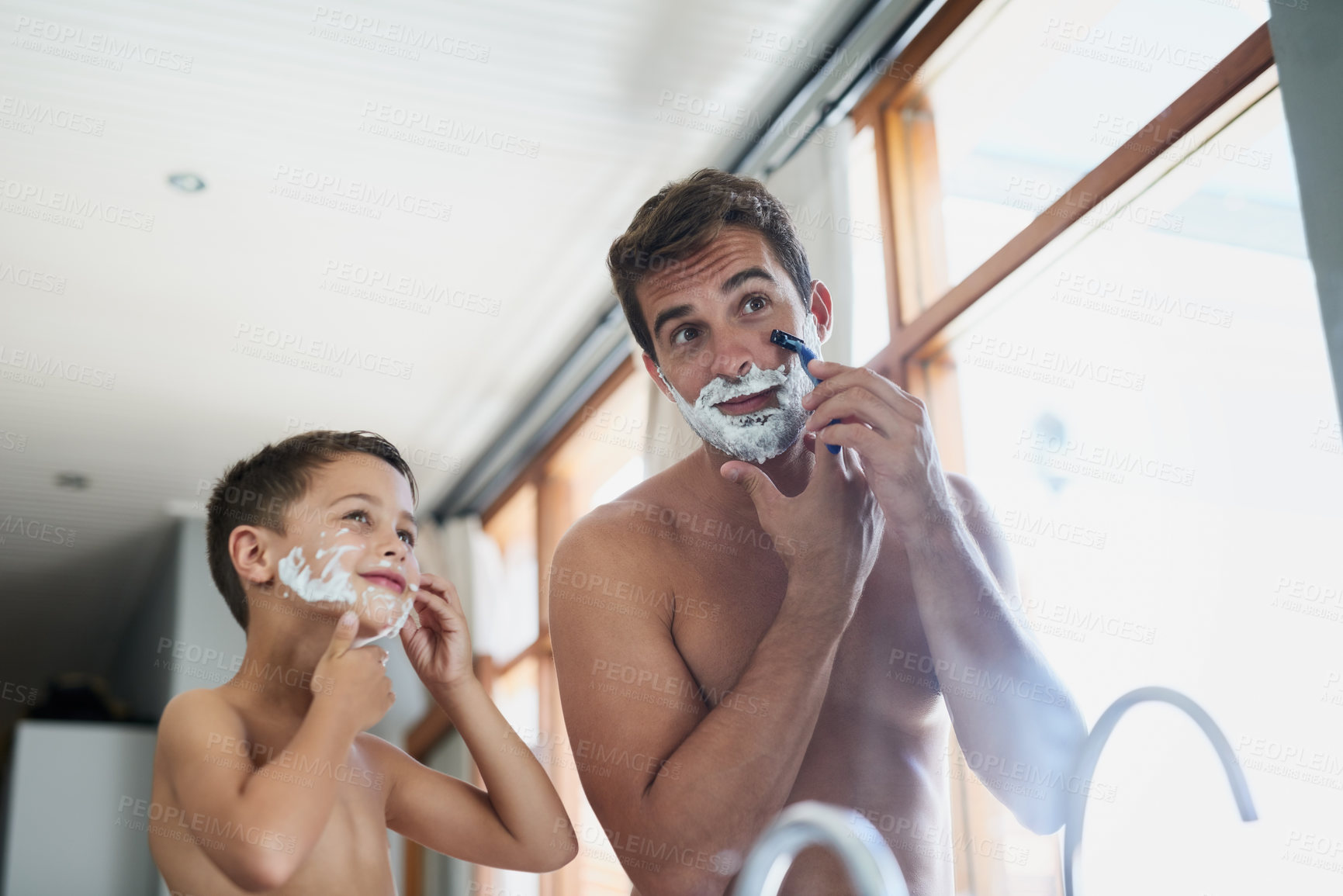 Buy stock photo Cropped shot of a handsome young man teaching his son how to shave in the bathroom