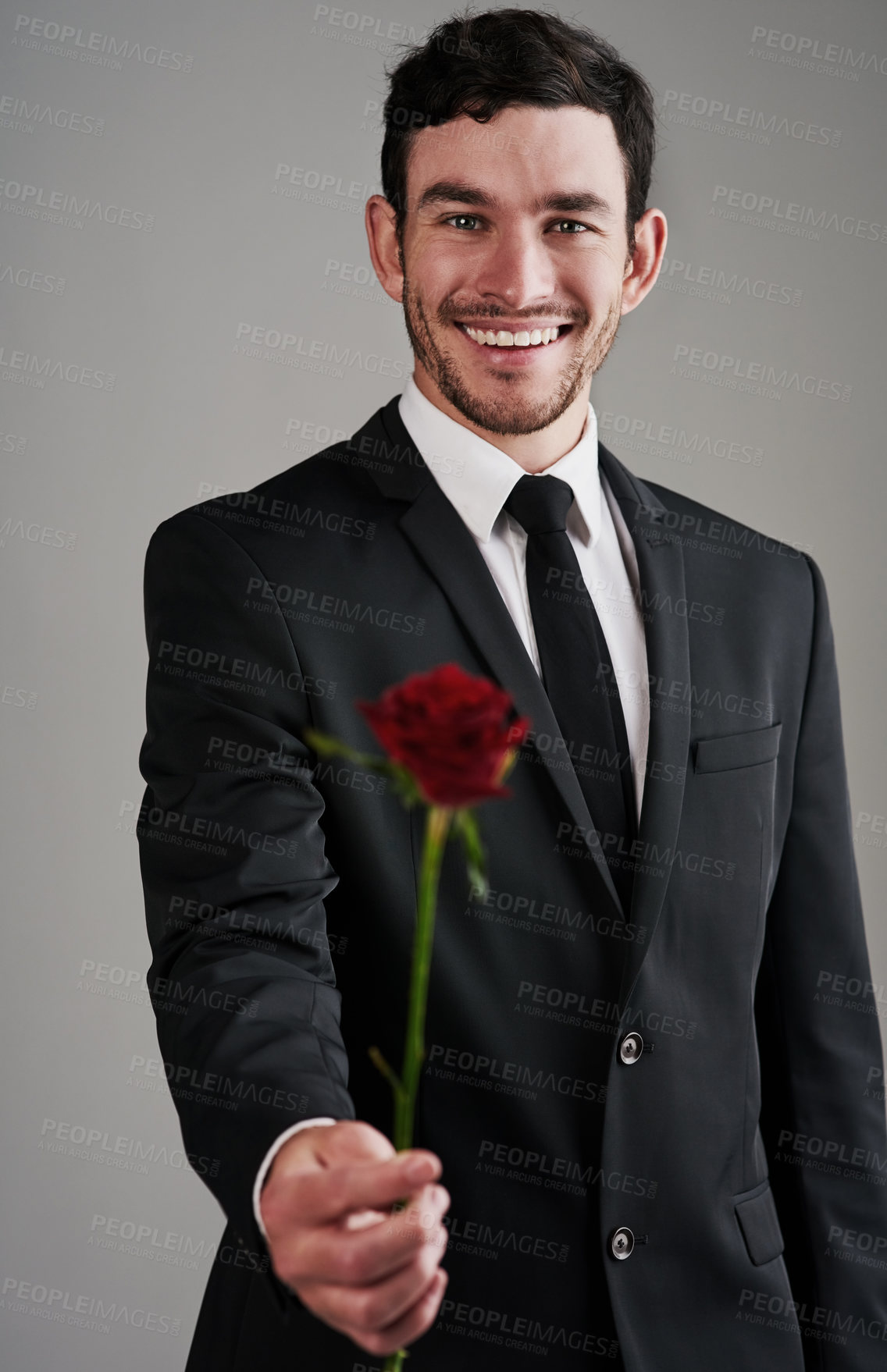 Buy stock photo Studio shot of a well-dressed man holding a red rose against a gray background