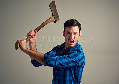Buy stock photo Studio shot of a young male lumberjack holding an axe against a grey background