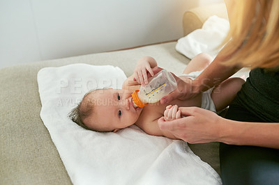 Buy stock photo Drinking, mother and feeding baby milk on sofa for growth development, nutrition or health. Lens flare, woman parent and infant child with bottle for formula, wellness or bonding with love in home