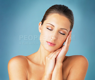Buy stock photo Studio shot of a beautiful young woman feeling her skin against a blue background