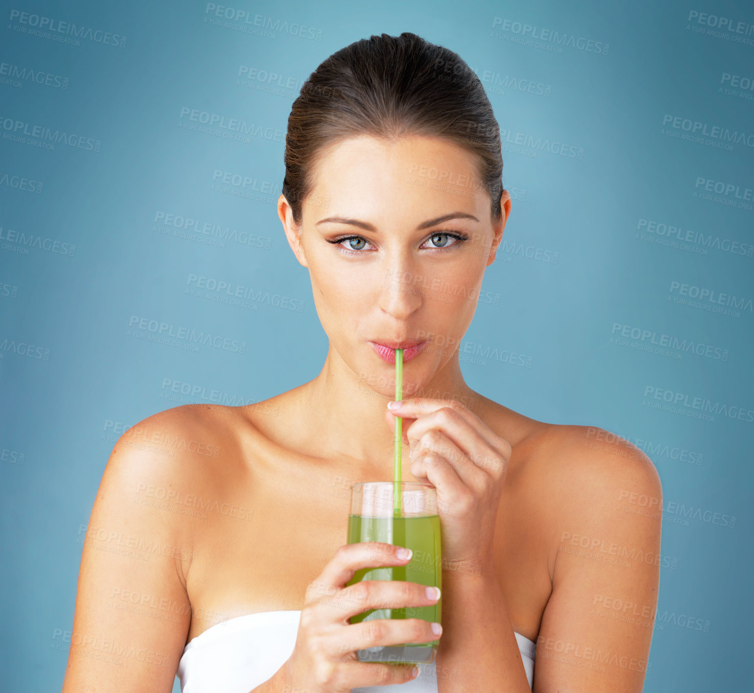 Buy stock photo Studio portrait of a beautiful young woman drinking a healthy green beverage against a blue background