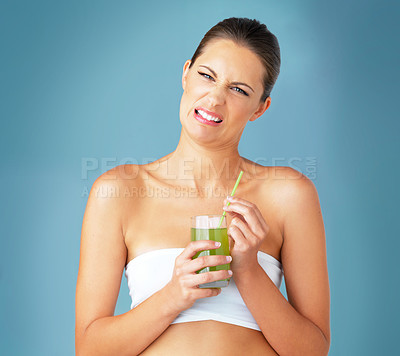 Buy stock photo Juice, portrait and woman in studio with disgust for minerals, vitamin C or healthy beverage on blue background. Diet, glass and model with green smoothie for wellness, antioxidants or nutrition