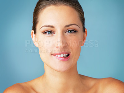 Buy stock photo Studio portrait of a beautiful young woman biting her lip against a blue background