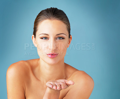 Buy stock photo Studio portrait of a beautiful young woman blowing a kiss against a blue background