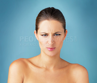 Buy stock photo Studio portrait of a beautiful young woman looking angry against a blue background