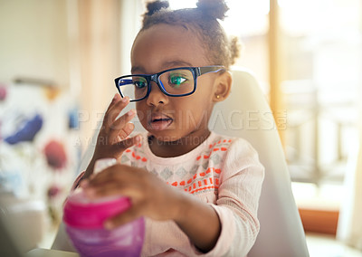 Buy stock photo Black child, glasses and thinking in home for vision, play and curious in high chair. Little girl, prescription spectacles and eye care in kitchen for sight, development and learning observation