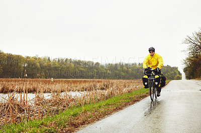 Buy stock photo Full length shot of a male cyclist enjoying a bike ride on a wet winter's morning