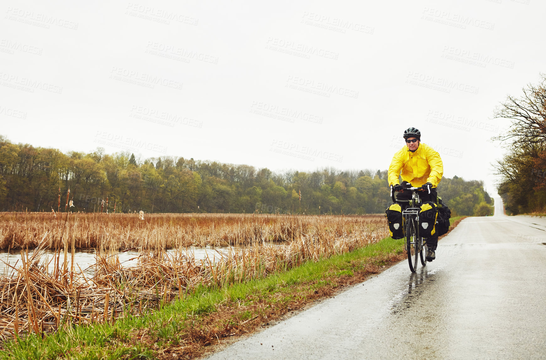 Buy stock photo Full length shot of a male cyclist enjoying a bike ride on a wet winter's morning