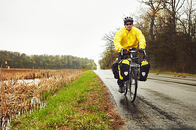 Buy stock photo Full length shot of a male cyclist enjoying a bike ride on a wet winter's morning