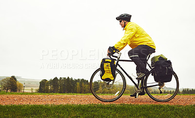 Buy stock photo Full length shot of a male cyclist enjoying a bike ride on a wet winter's morning