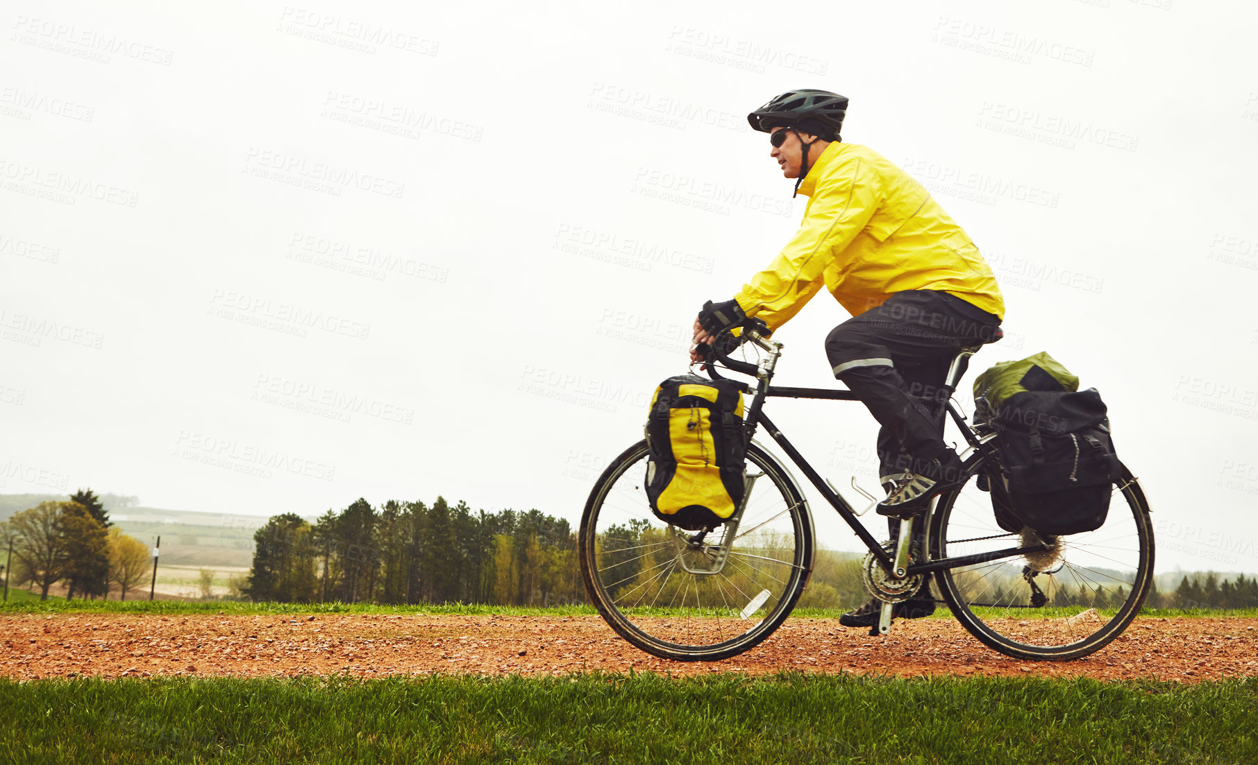 Buy stock photo Full length shot of a male cyclist enjoying a bike ride on a wet winter's morning