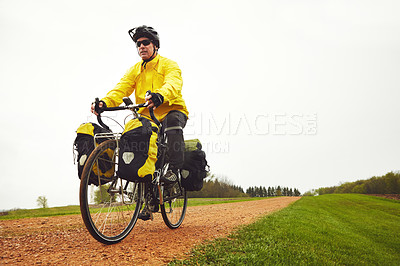 Buy stock photo Full length shot of a male cyclist enjoying a bike ride on a wet winter's morning