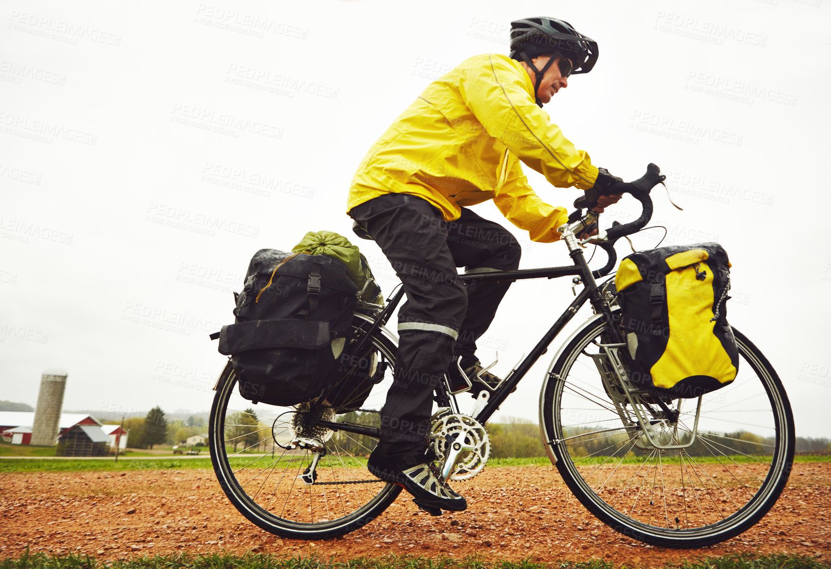 Buy stock photo Full length shot of a male cyclist enjoying a bike ride on a wet winter's morning