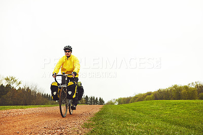 Buy stock photo Full length shot of a male cyclist enjoying a bike ride on a wet winter's morning