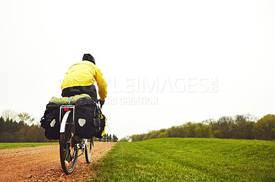 Buy stock photo Rearview shot of a male cyclist enjoying a bike ride on a wet winter's morning