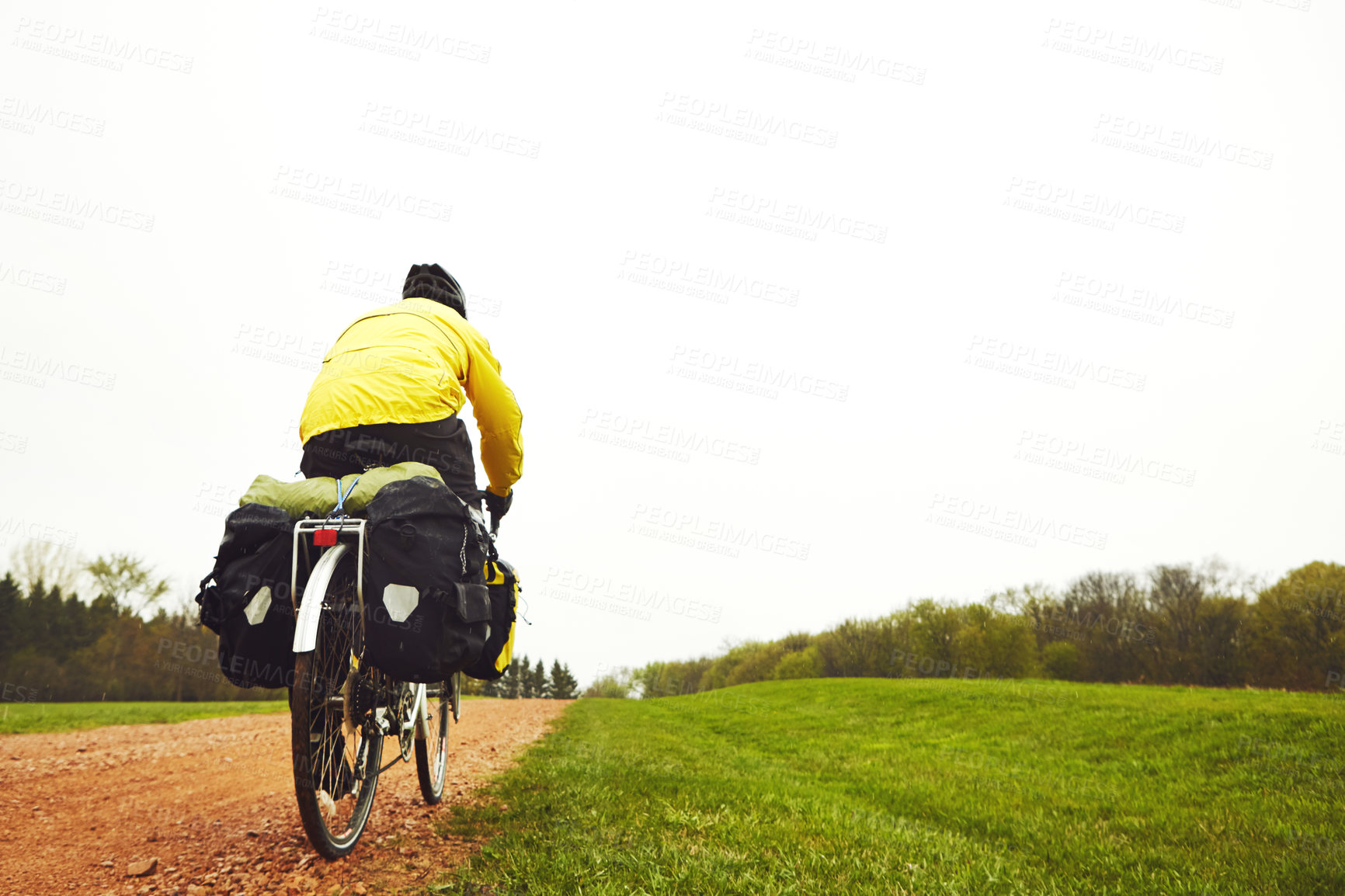 Buy stock photo Rearview shot of a male cyclist enjoying a bike ride on a wet winter's morning