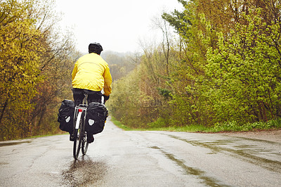 Buy stock photo Rearview shot of a male cyclist enjoying a bike ride on a wet winter's morning