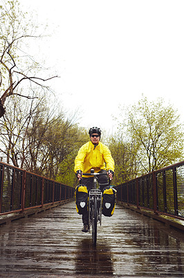 Buy stock photo Full length shot of a male cyclist enjoying a bike ride on a wet winter's morning