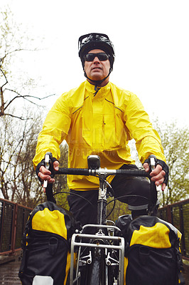 Buy stock photo Cropped shot of a male cyclist enjoying a bike ride on a wet winter's morning